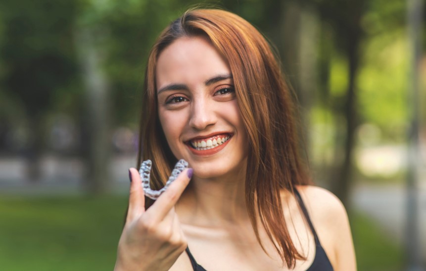 beautiful smiling turkish woman holding invisalign