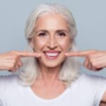 smiling women pointing on new dentures