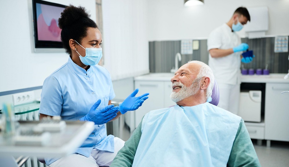 Dental assistant prepares senior man for tooth extraction