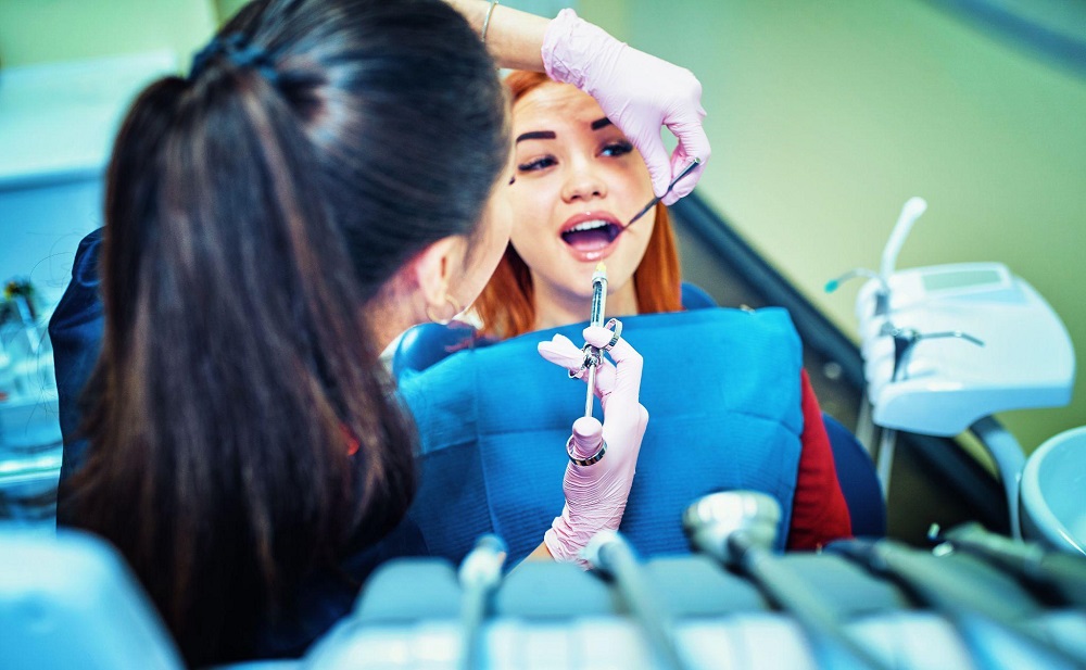 Female patient sitting in dental chair being prepped for tooth extraction