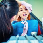 Female patient sitting in dental chair being prepped for tooth extraction