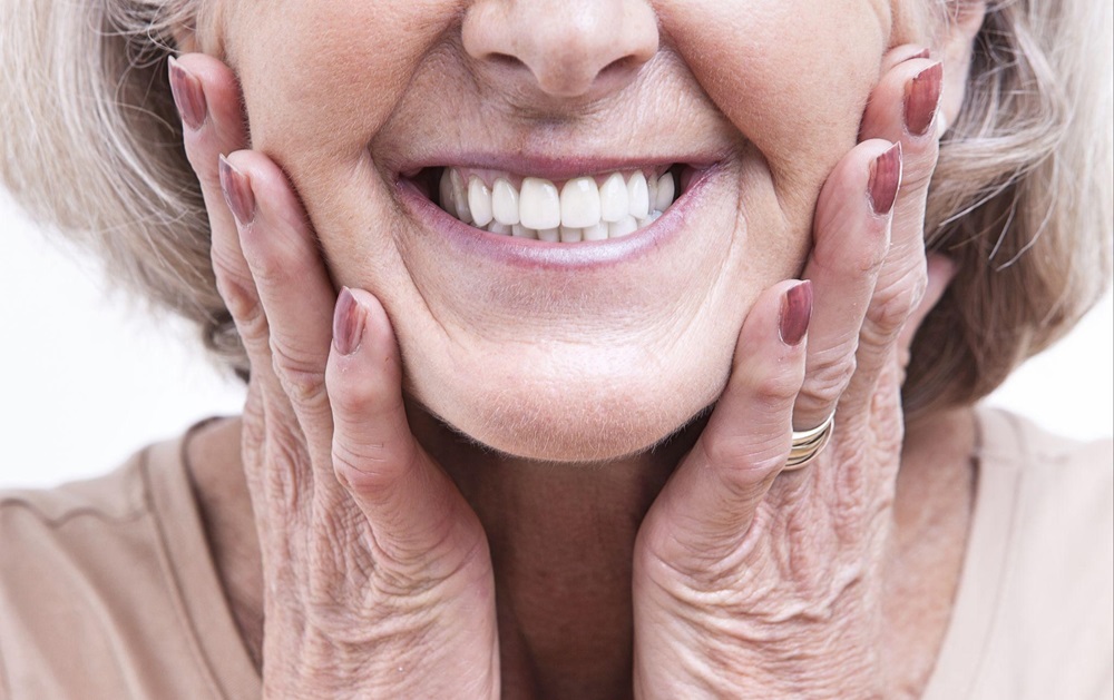 Closeup of a senior woman's mouth, smiling to show her dentures