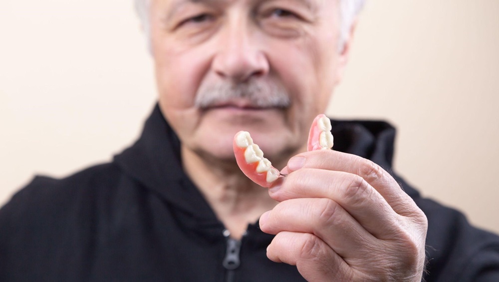 Senior man holding his lower denture