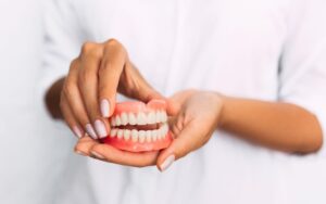 Woman's hands holding a pair of dentures