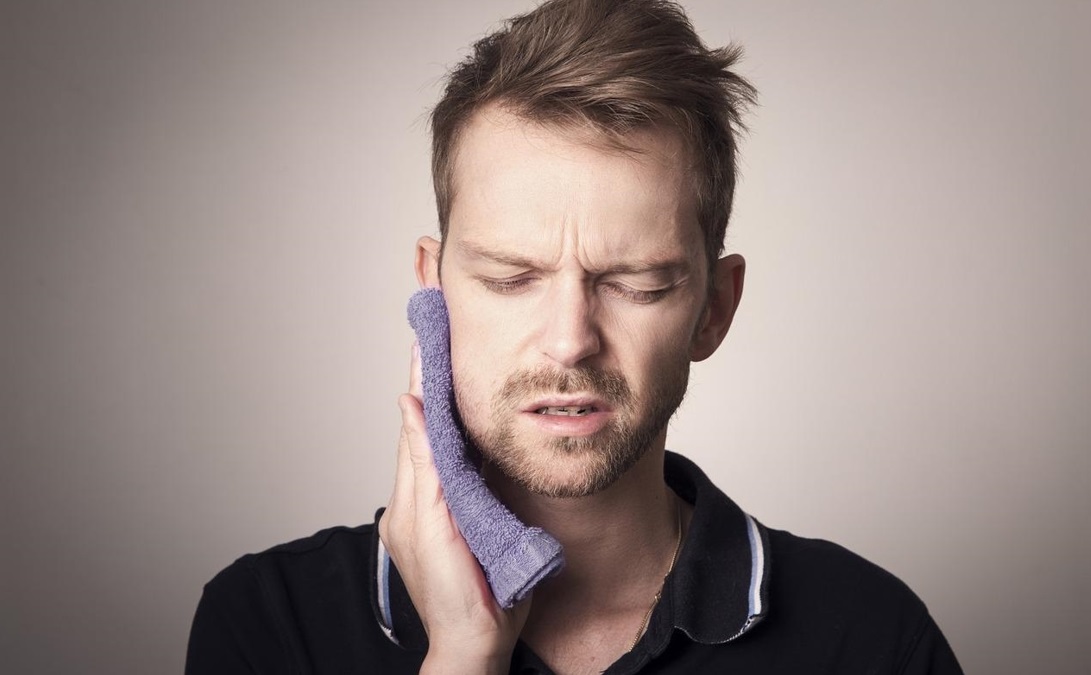 Man with toothache holding a cloth to his cheek