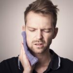 Man with toothache holding a cloth to his cheek